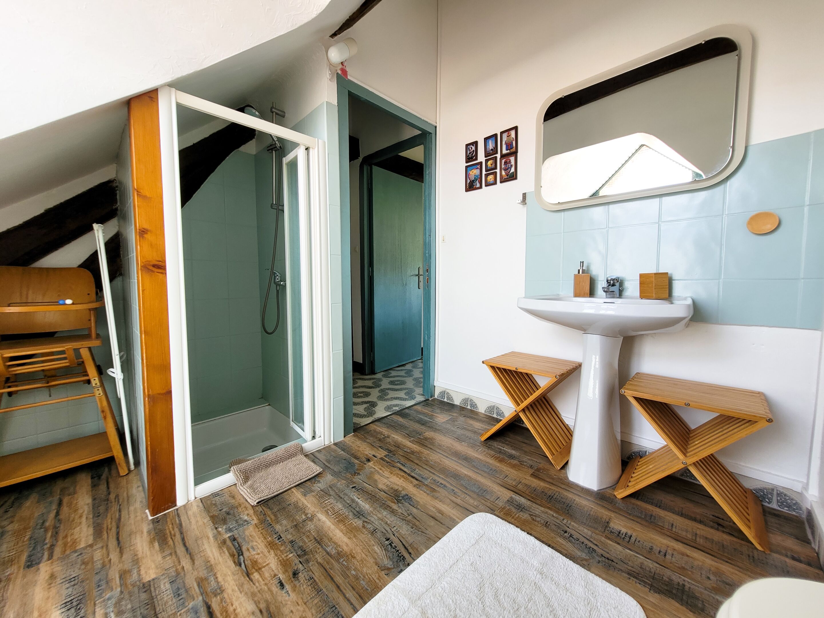 Un baño con banca de madera, lavamanos y ducha.
