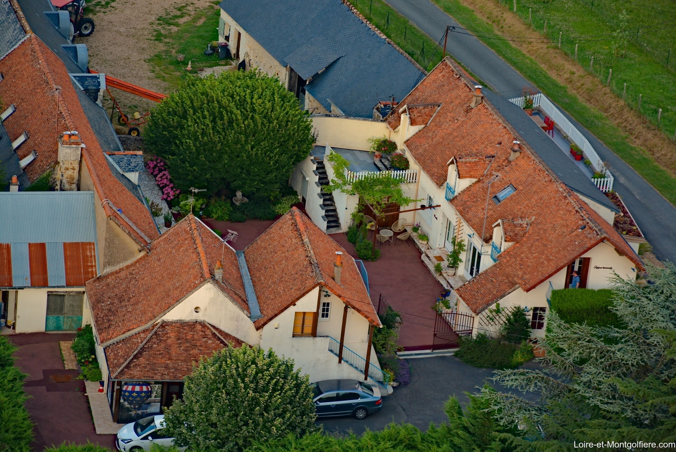 Een woonwijk met huizen met rode dakpannen, een verharde weg en een auto geparkeerd voor een van de huizen.