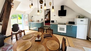 Una cocina acogedora con una mesa de comedor de madera, armarios azules y una lámpara colgante.