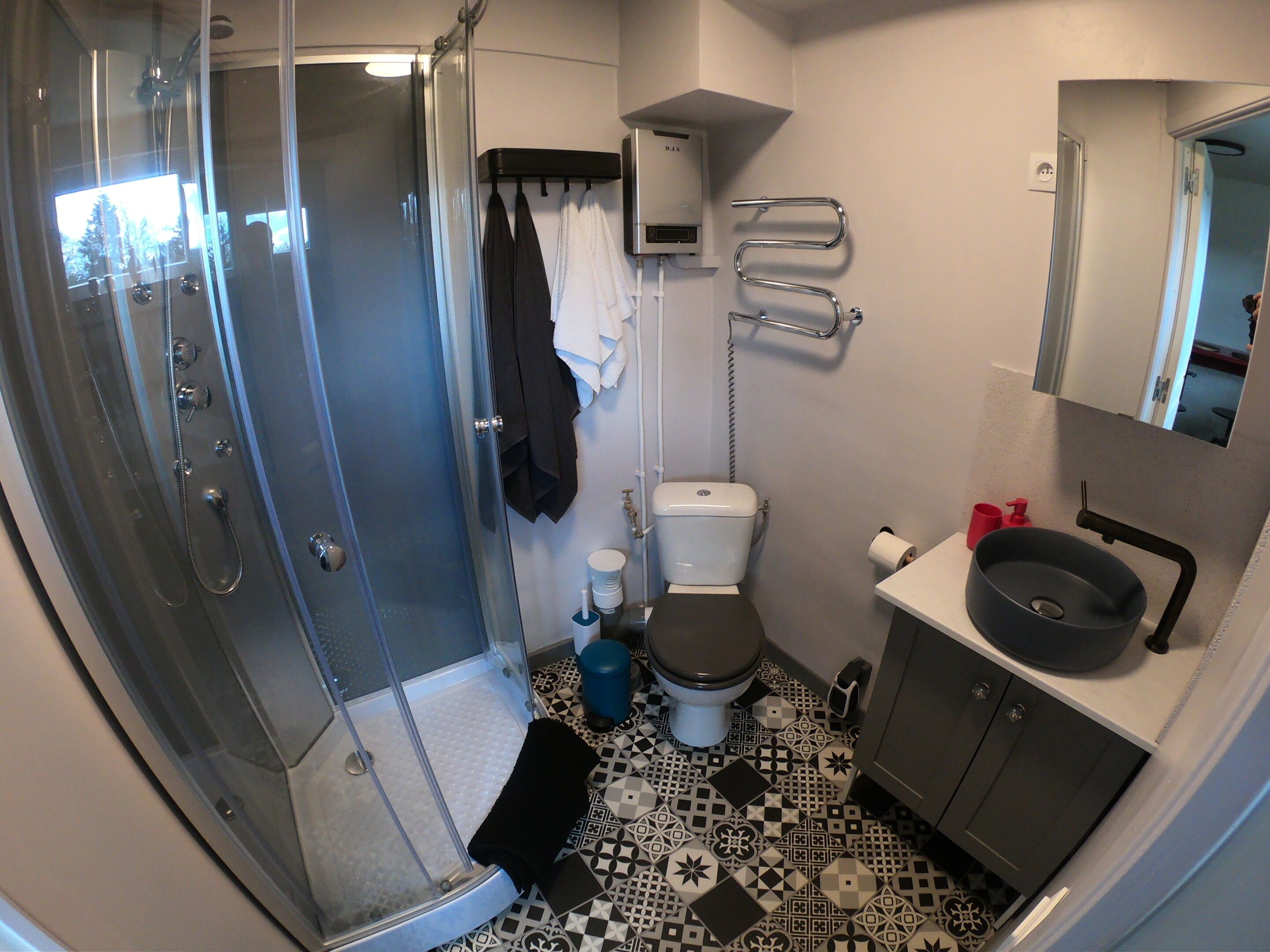 Ein Badezimmer mit einer Duschkabine aus Glas, einer Toilette, einem Waschbecken und einem Spiegel darüber.