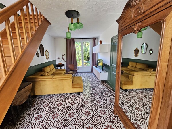 Une pièce avec un sol à motifs, un canapé, un miroir et un escalier.