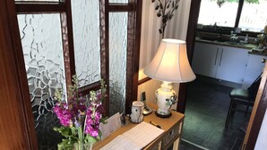 A wooden table with a vase of purple flowers, a lamp, a calendar, and a menu. - Foinaven Bed & Breakfast (Ullapool)