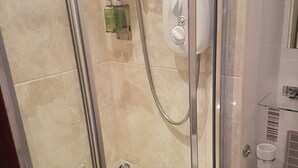 A glass-enclosed shower with a handheld showerhead, a wall-mounted control panel, and a glass shelf with toiletries. - Foinaven Bed & Breakfast (Ullapool)