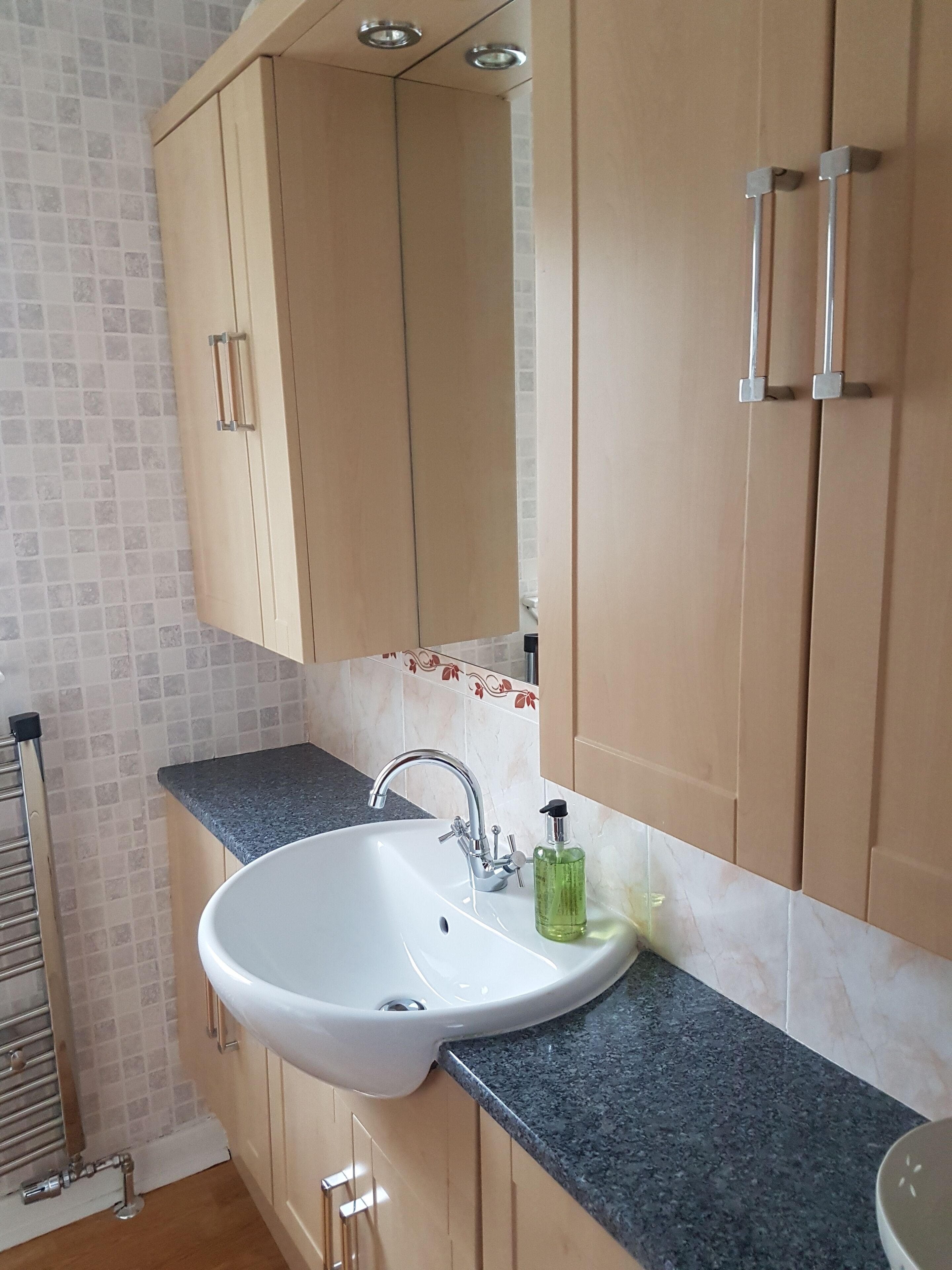 A bathroom with a white sink, a mirror, and wooden cabinets.