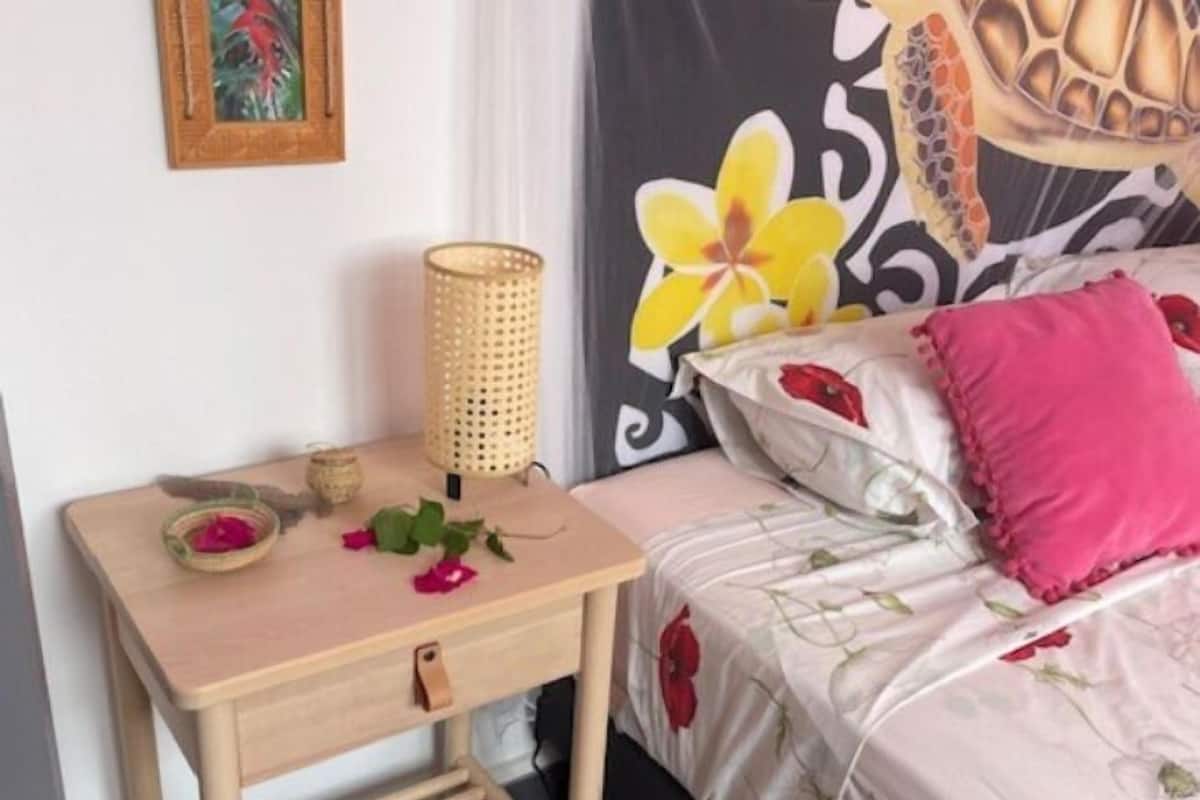 A neatly arranged bedroom with a bed, a bedside table with a lamp, and a wall decoration.