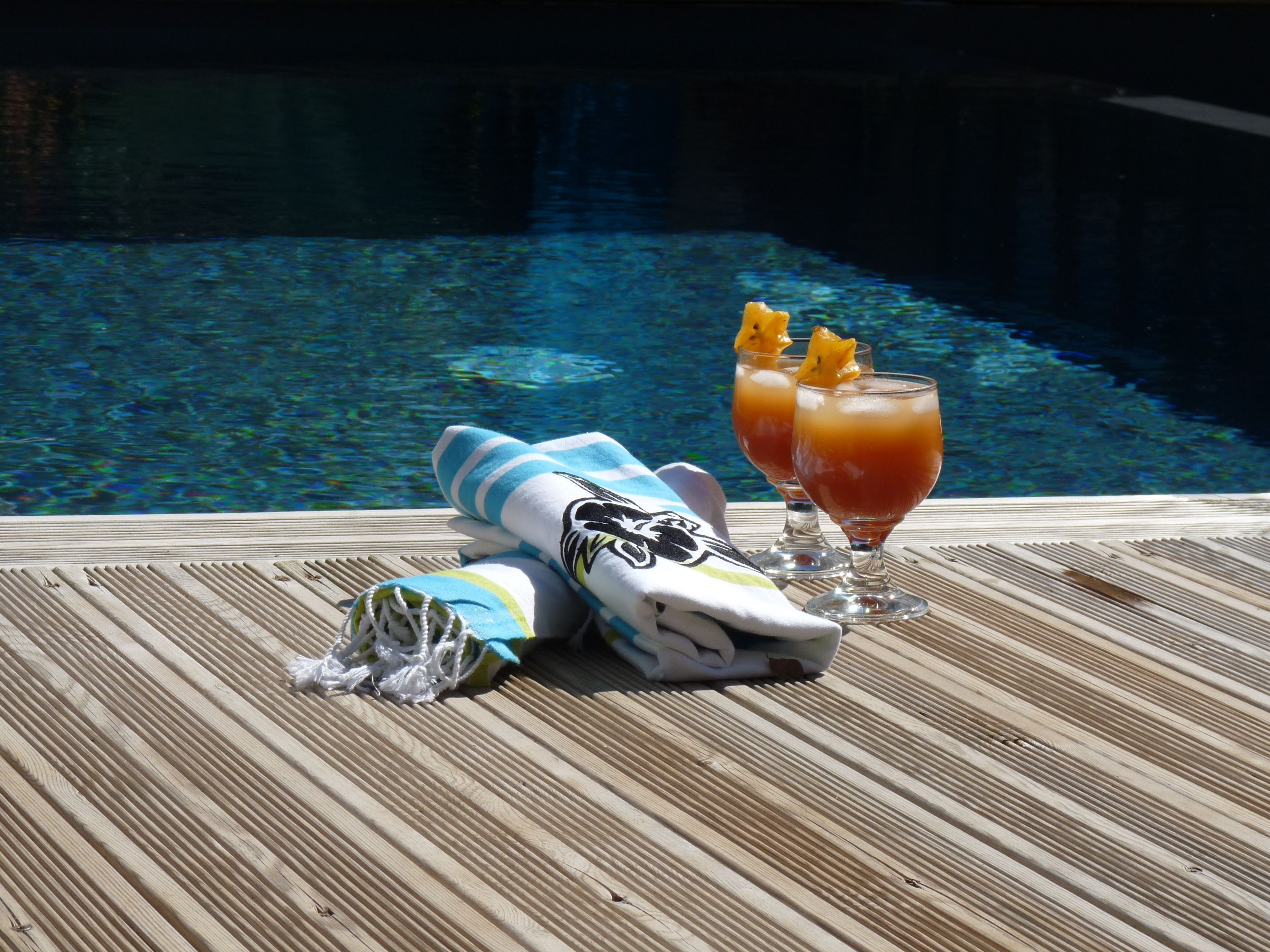 Un endroit agréable au bord de la piscine, avec une boisson et une serviette.