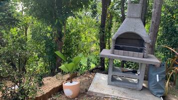 Una parrilla de piedra en un jardín, con una planta en maceta cerca.