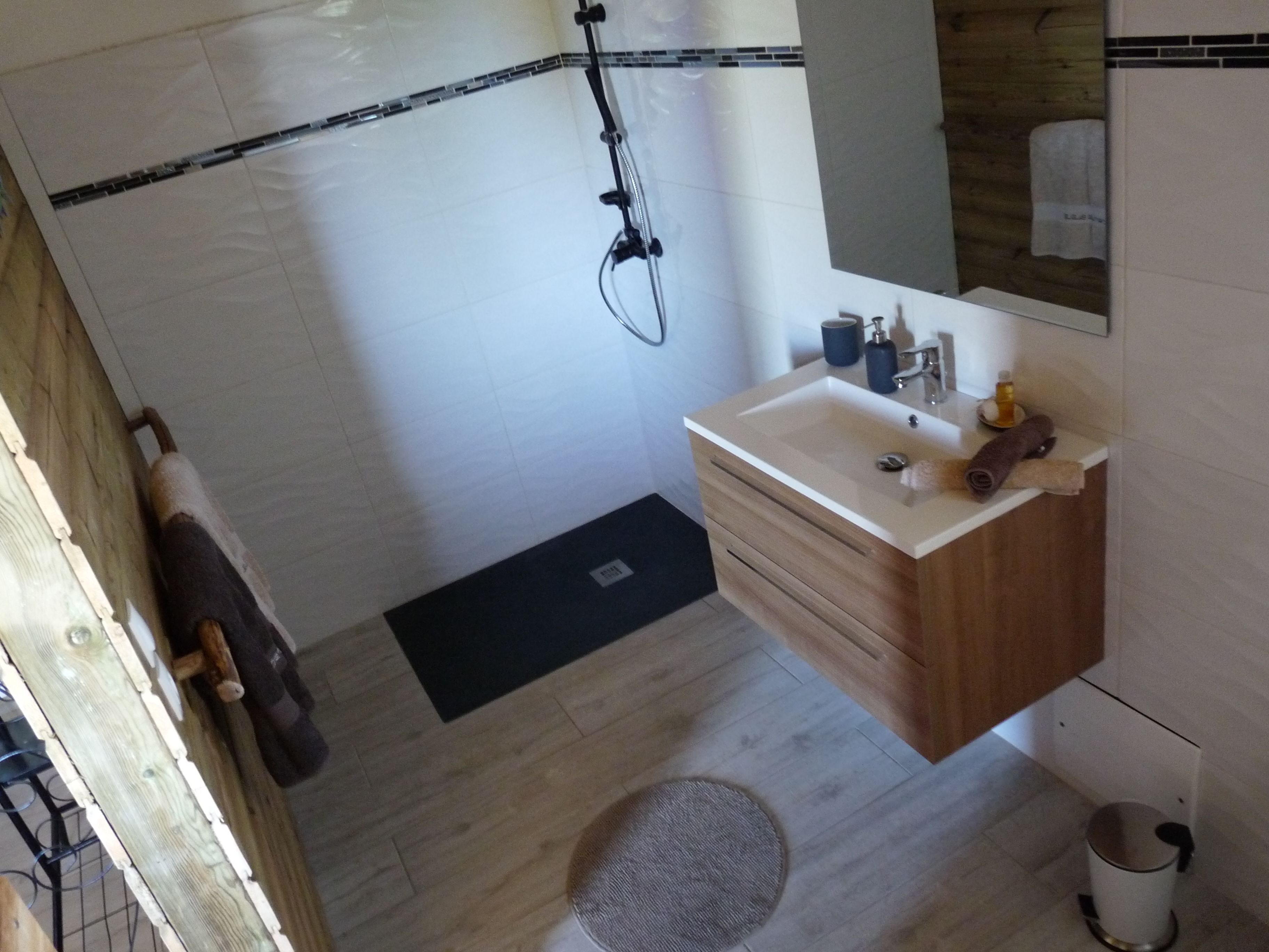 Un baño con tocador de madera, un espejo, un lavabo y una ducha.
