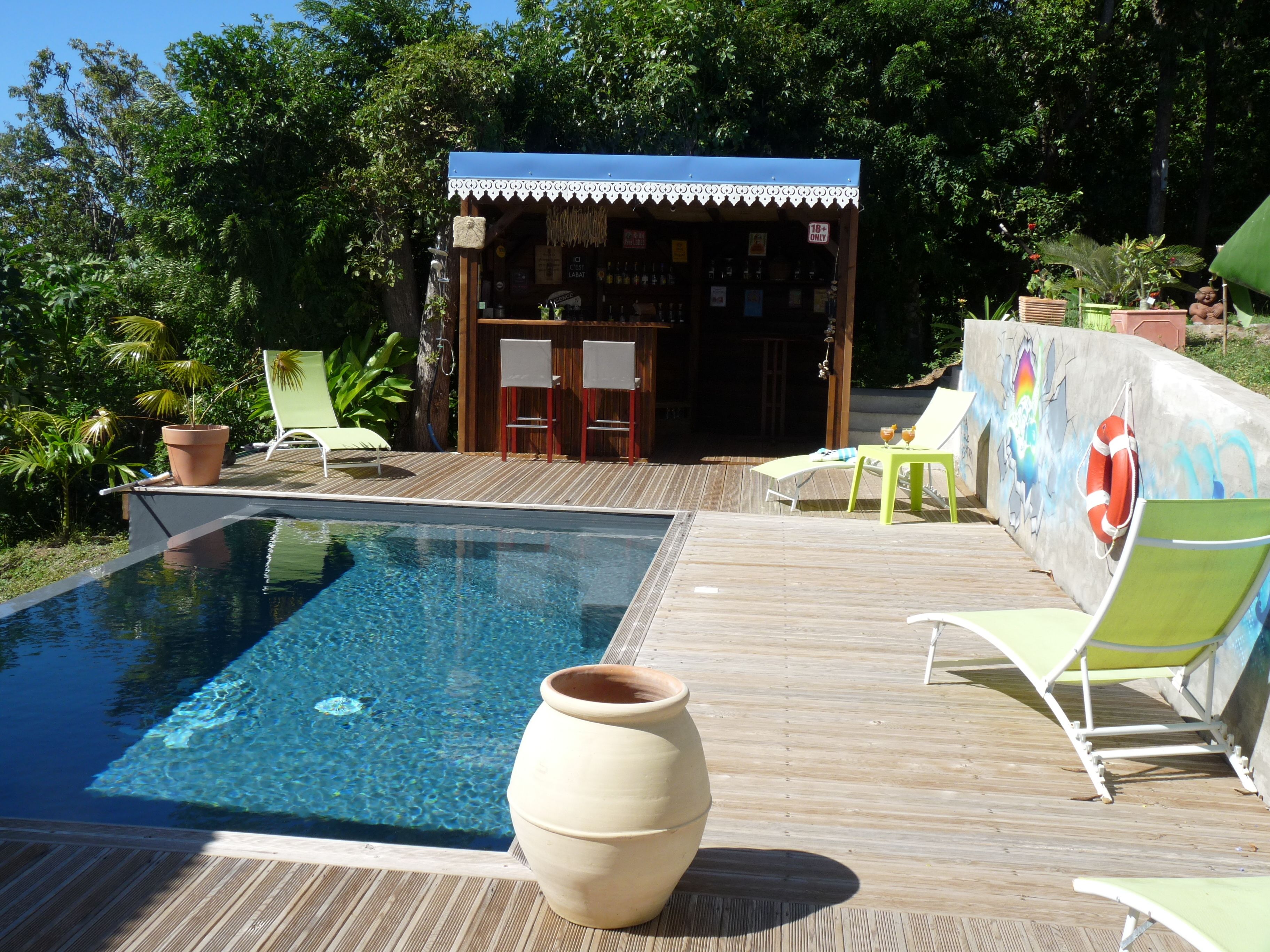 A pool area with a wooden deck, lounge chairs, and a bar area with a sign indicating an age restriction.