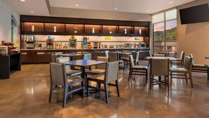 A modern hotel lobby with a spacious seating area, a kitchen counter, and a large window offering a view of the outdoors. - GLō Hotel Asheville-Blue Ridge Parkway (Asheville)