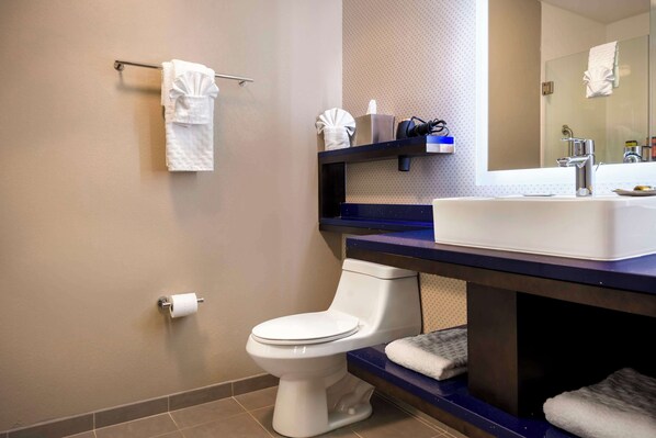 A modern bathroom with a white toilet, a sink with a mirror, and a towel rack.