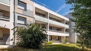 A multi-story building with balconies, a flat roof, and a small garden area. - Tempologis - Meylan (Meylan)