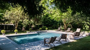 A rectangular swimming pool with lounge chairs and potted plants around it. - Hôtel Chavant (Bresson)
