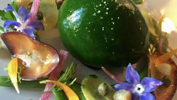 A plate with a green fruit, possibly a lime, surrounded by various vegetables and flowers.