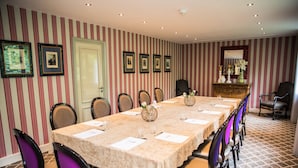 A conference room with a long table, chairs, framed pictures, and a mirror on the wall. - Hôtel Chavant (Bresson)