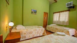 Quarto com duas camas, uma porta de madeira, televisão presa à parede e um quadro pequeno.
