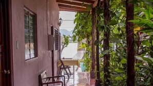 Um corredor com piso de azulejos, bancos de madeira e plantas em vasos.