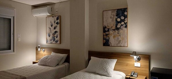 A hotel room with two beds, a wooden headboard, bedside lamps, and wall art. - Pinhal Palace Hotel (Espirito Santo Do Pinhal)