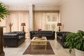 A living room with a black leather sofa set, a coffee table, and two floor lamps. - Pinhal Palace Hotel (Espirito Santo Do Pinhal)