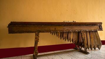 Una larga mesa de madera con intrincados grabados y un diseño único, ubicada frente a una pared amarilla con zócalo rojo.