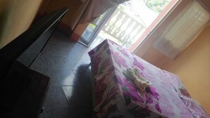 A room with a tiled floor, a table with a floral tablecloth, and a window with curtains. - Hotel Aurora (Flores)