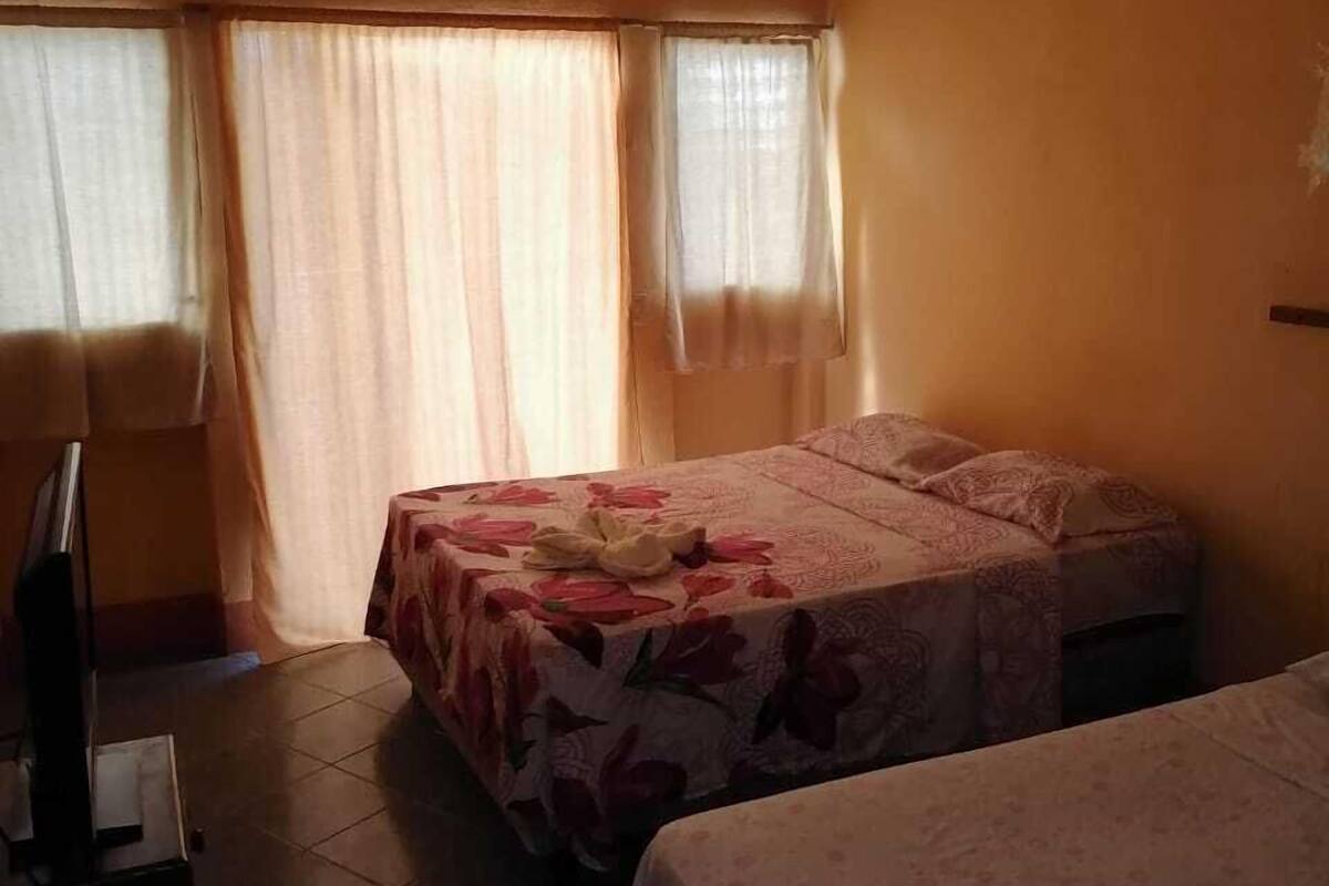 Une chambre d’hôtel avec deux lits, une télévision et un fauteuil.