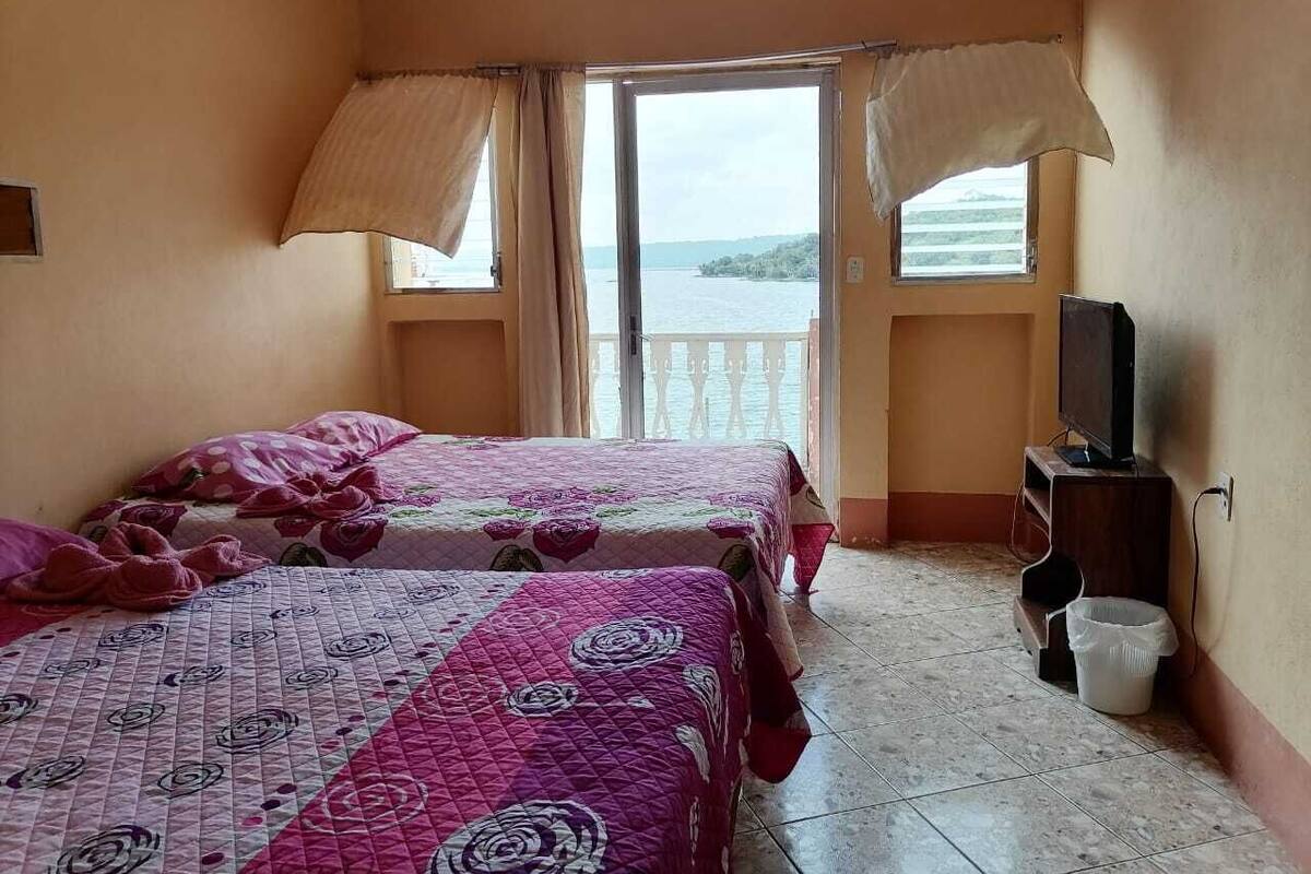 Une chambre avec deux lits, une télévision et un balcon donnant sur la mer.