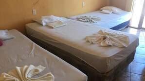 Two single beds with towels folded on them, a tiled floor, and a plain wall with a power outlet. - Hotel Aurora (Flores)