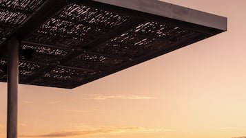 Una construcció moderna a l'aire lliure amb un paviment reflectant, amb vista a una mar tranquil·la al capvespre.