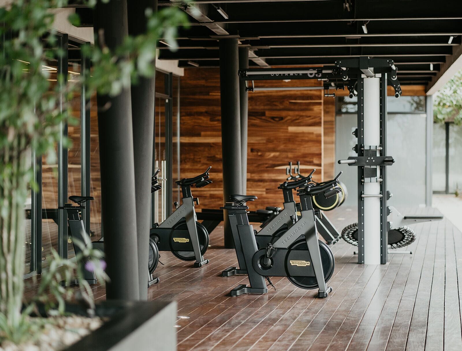 A gym with stationary bikes, wooden flooring, and a modern design.
