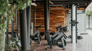 A gym with stationary bikes, wooden flooring, and a modern design.
