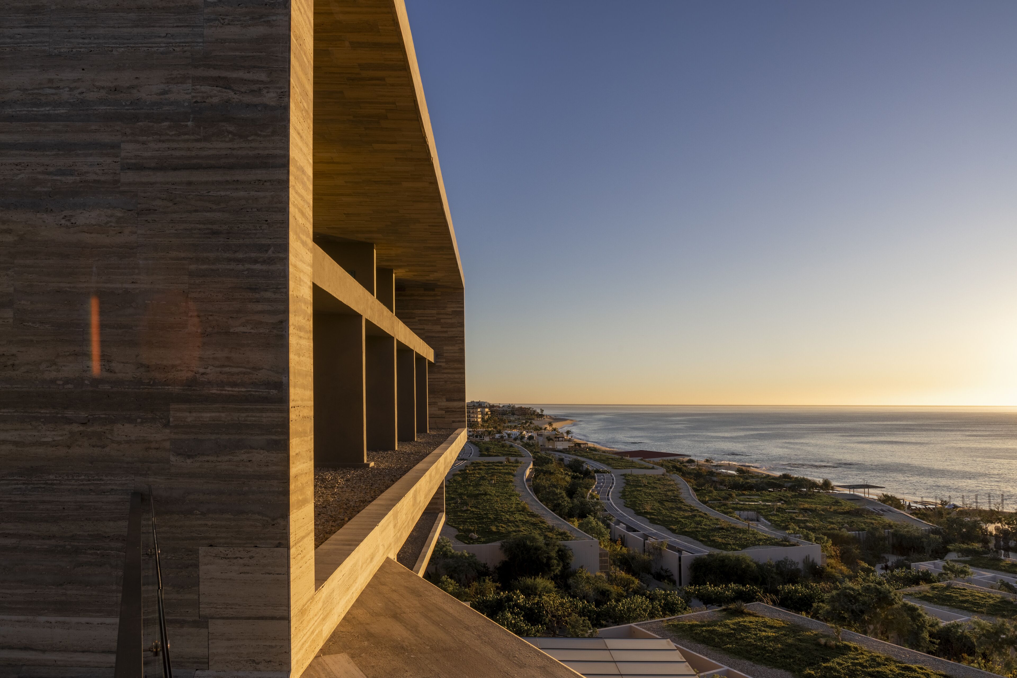 A modern building with a curved facade overlooking a coastal landscape.
