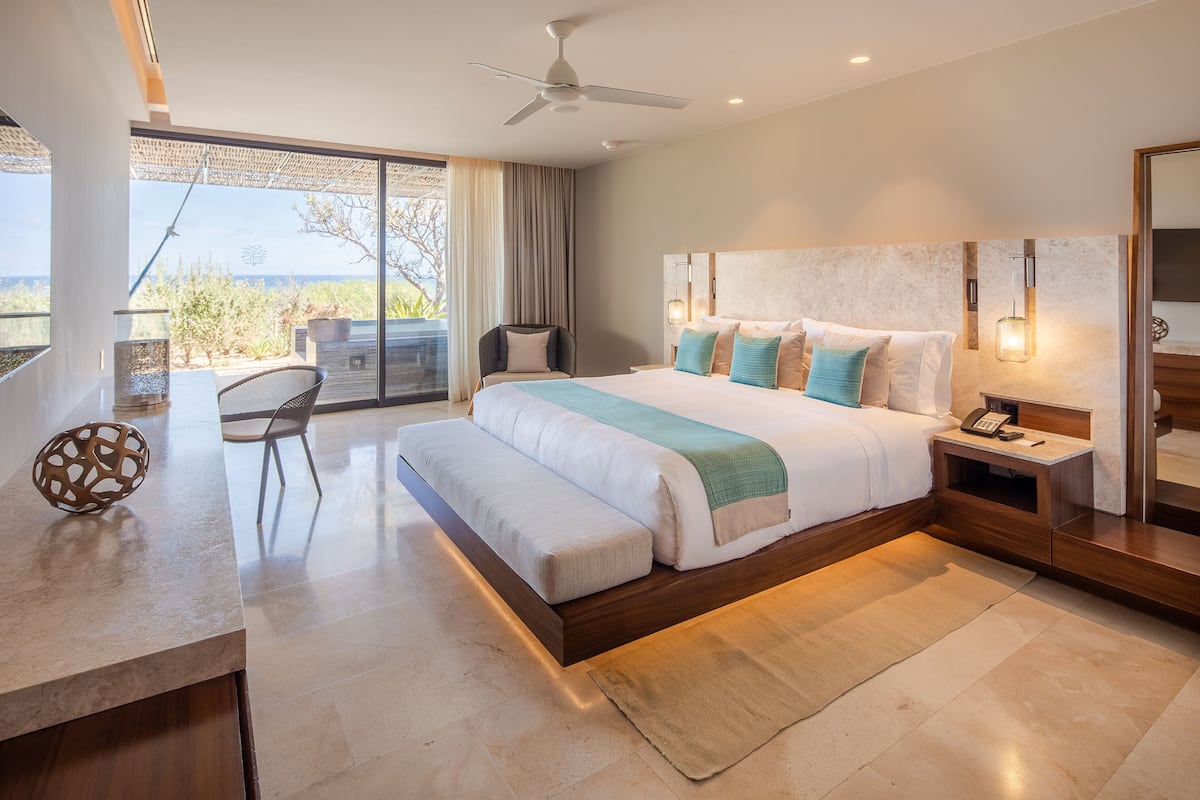 A modern bedroom with a large bed, a desk, and a chair.