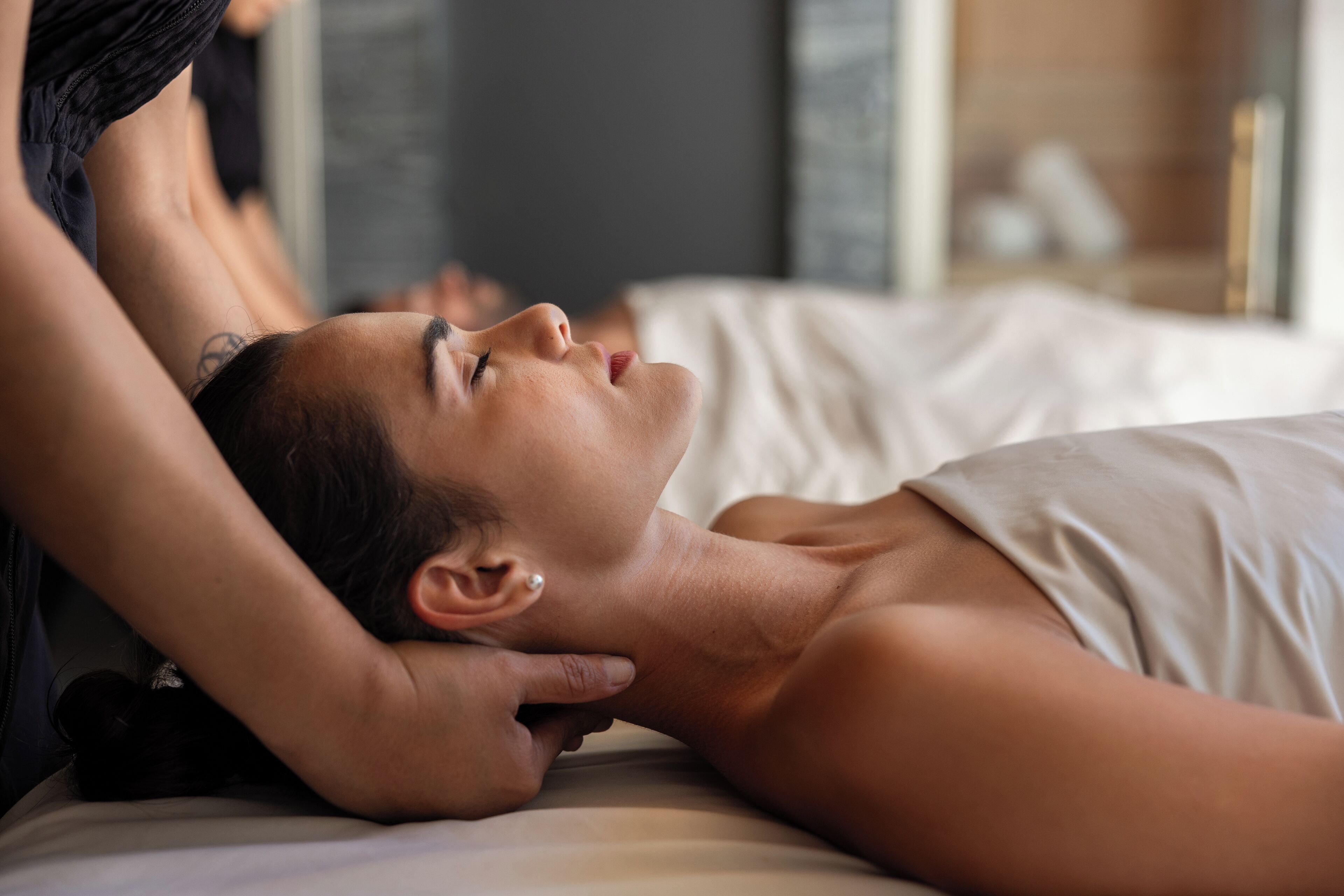 A person lying on a bed in a room with a window and a mirror.