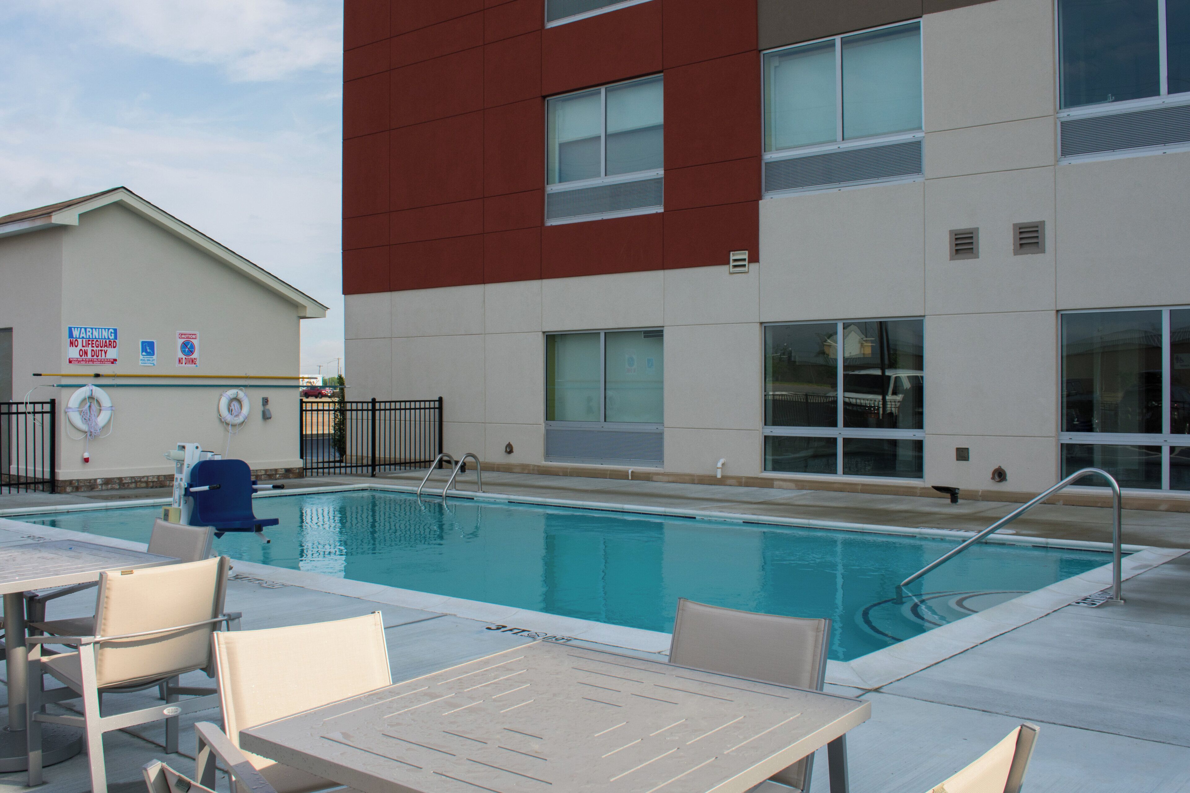 A swimming pool with lounge chairs and a lifeguard stand.
