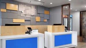 A reception desk with a blue accent, a wooden panel design on the wall, and a refrigerator with beverages. - Holiday Inn Express and Suites West Memphis by IHG (West Memphis)
