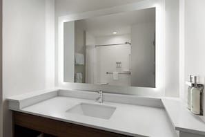 A modern bathroom with a white sink, a large mirror, and a shower area visible in the reflection. - Holiday Inn Express and Suites West Memphis by IHG (West Memphis)
