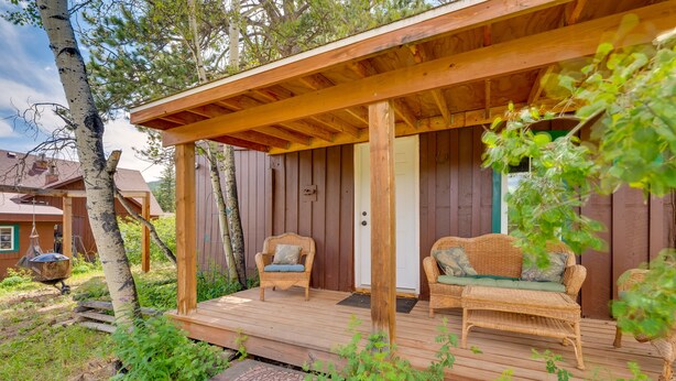 A wooden cabin with a porch, wicker furniture, and a door. - 'Wapiti' Allenspark Cabin Near Rocky Mountains! (Allenspark)