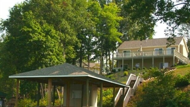 A two-story house with a balcony, surrounded by trees and a dock. - 5 o'clock Somewhere - Pool Table, Walking Distance to Portside Bar & Grill, Just Like New! (Moneta)