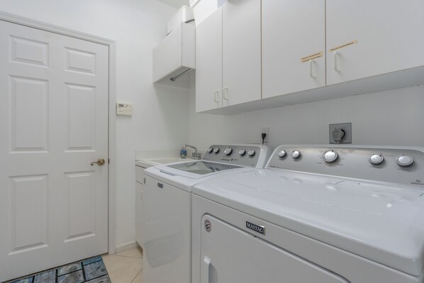 A laundry room with a white washing machine, a dryer, and a white door.