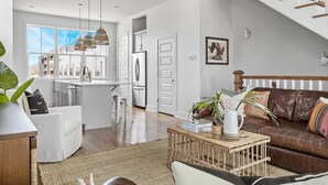 A modern kitchen with white cabinets, a stainless steel refrigerator, and pendant lights.