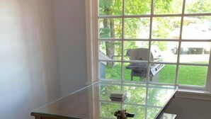 Een eettafel met glazen blad, vier houten poten en bijpassende bankjes in een kamer met lichtgekleurde muren en vloer.