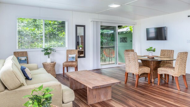 Un vaste espace de vie comprenant un canapé, une table basse, des fauteuils en osier et une table à manger.