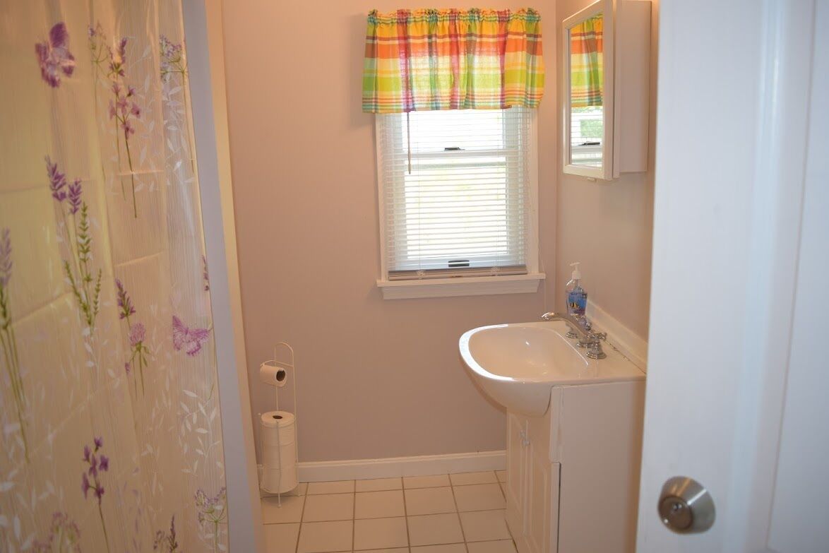 A bathroom with a toilet, sink, and window with blinds.