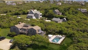 An aerial view of a residential area with multiple houses surrounded by dense greenery.