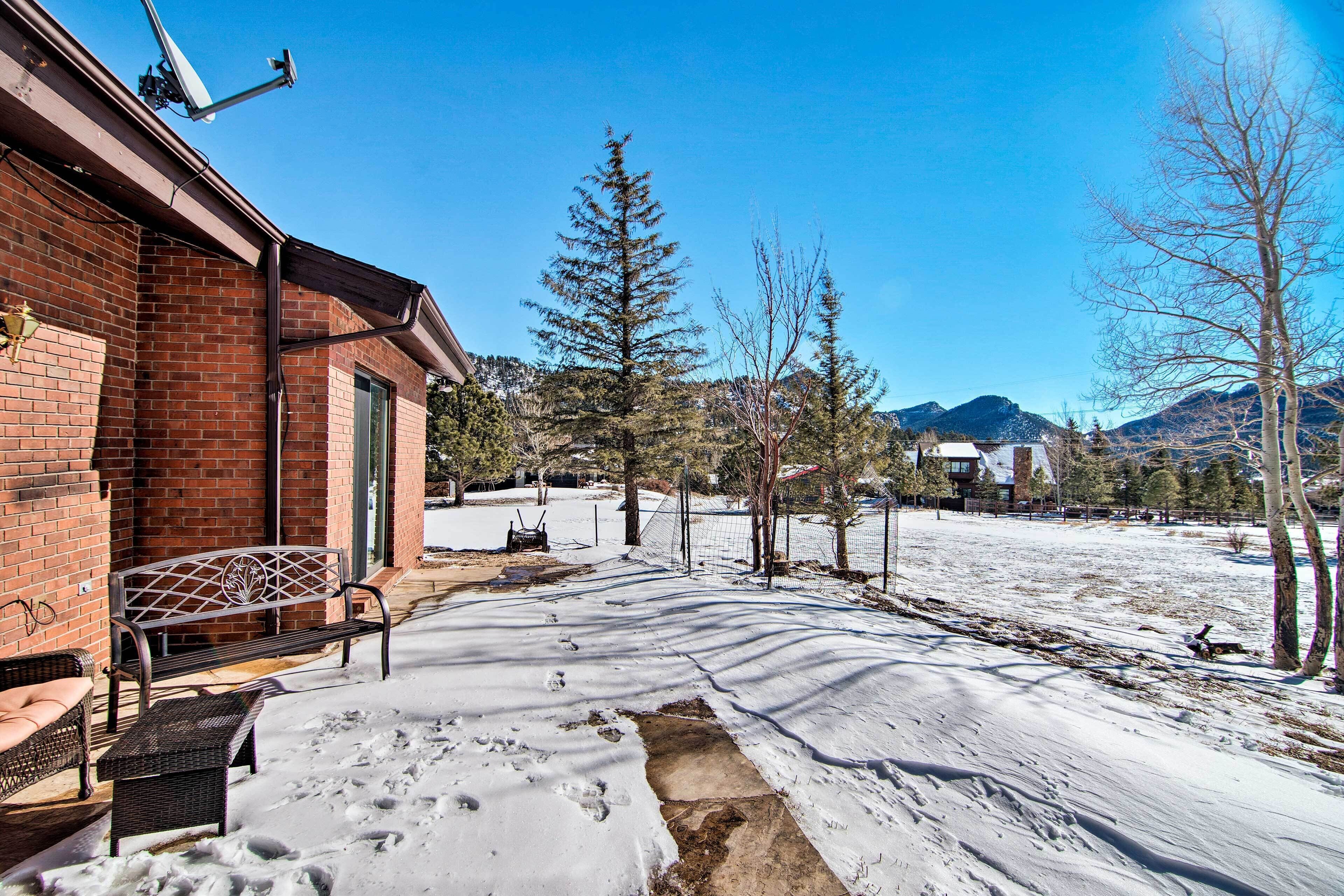 Un espacio exterior cubierto de nieve con un edificio de ladrillo, un banco y un sendero que lleva a una casa.