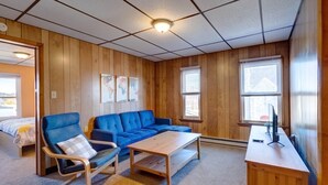 A room with wooden walls, a blue sofa, a wooden coffee table, a blue armchair, and a small wooden desk with a TV. - Philip Arthur Suite, Apt #6
Hershey Penthouse overlooking all of Hershey (Hershey)