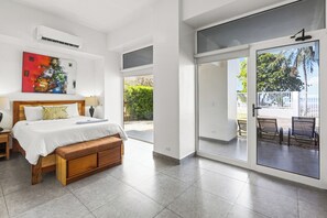 Un dormitorio con cama, mesita de noche, banco y un cuadro en la pared.