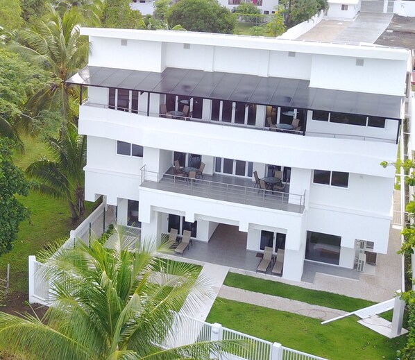 Un edificio moderno de varios pisos con techo plano, ventanas amplias y un balcón con mobiliario exterior.