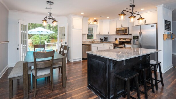 Una cocina moderna con una isla grande, electrodomésticos de acero inoxidable y un comedor con mobiliario de madera.